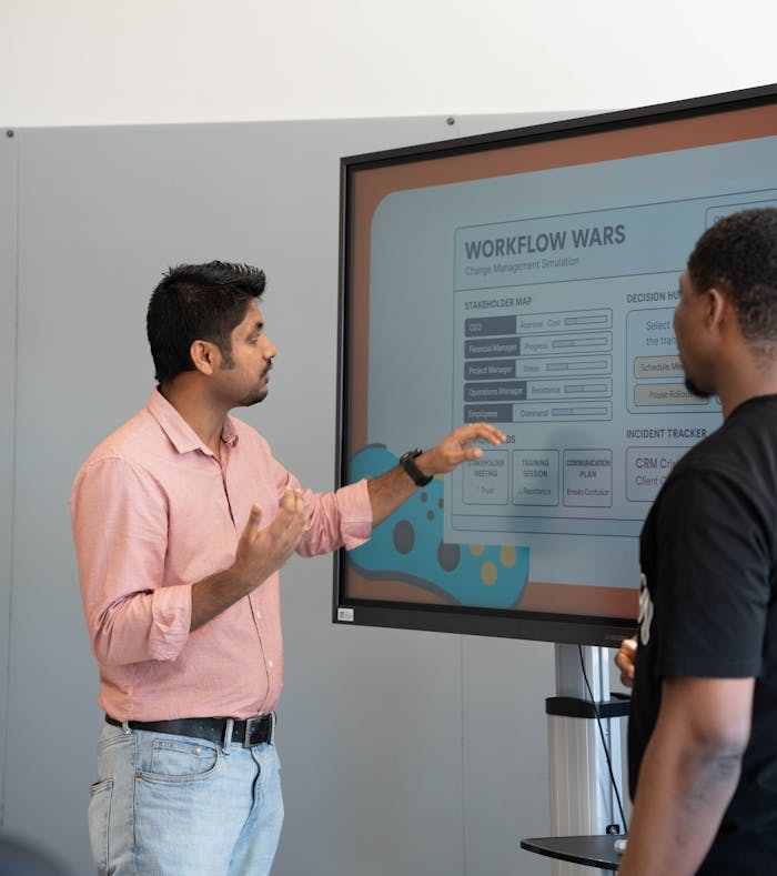menu-13 Two professionals engage in a workflow strategy discussion using a screen display.