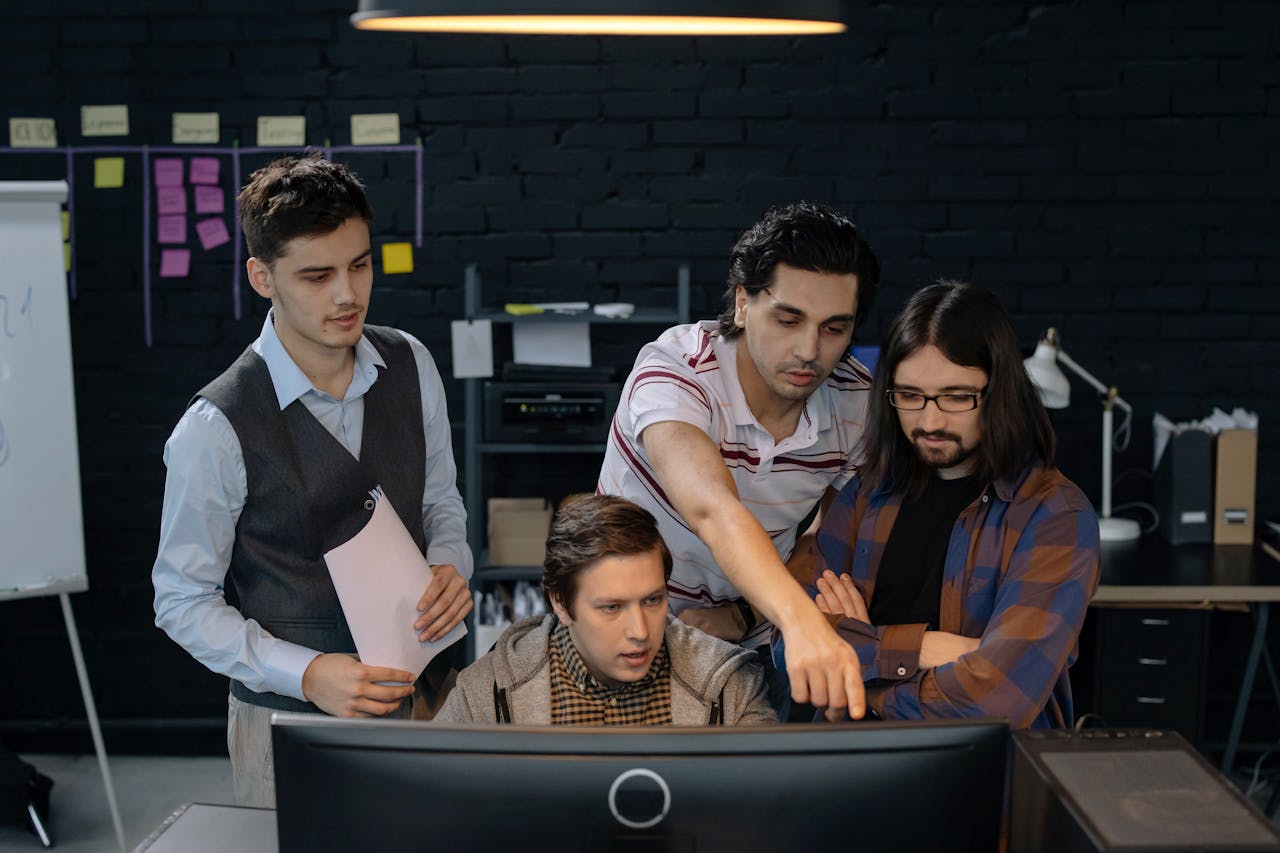 about-01 Group of professionals discussing a project at a computer in a modern office environment.