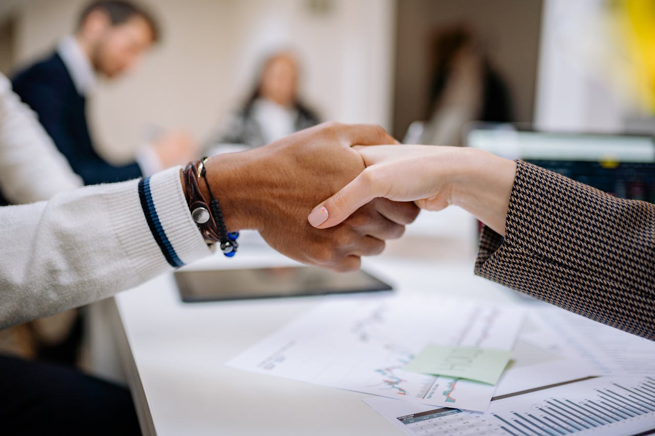 menu-07 Diverse business professionals exchanging handshake in an office environment, symbolizing agreement.